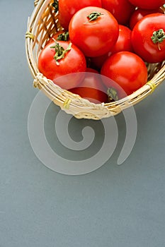 Fresh Ripe Organic Red Tomatoes in Wicker Basket on Grey Background. Mediterranean Cuisine. Healthy Food Ingredients. Poster