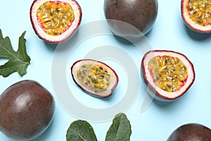 Fresh ripe passion fruits maracuyas with green leaves on light blue background, flat lay