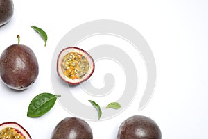 Fresh ripe passion fruits maracuyas with leaves on white background, flat lay. Space for text