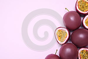 Fresh ripe passion fruits maracuyas on pink background, flat lay. Space for text