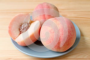 Fresh Ripe Peach Whole Fruits and a Cut Fruit on Blue Plate Served on Wooden Table