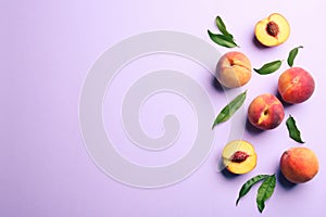 Fresh ripe peaches and green leaves on violet background, flat lay. Space for text
