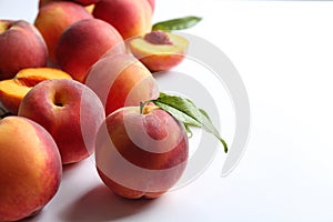 Fresh ripe peaches and green leaves on white background, closeup. Space for text