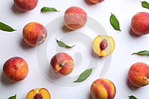 Fresh ripe peaches and green leaves on white background, flat lay