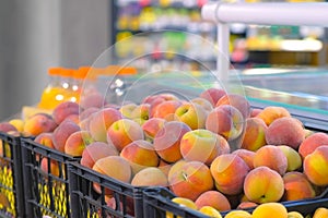 Fresh ripe peaches in plastic box ready for sale in supermarket, closeup view.