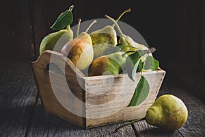 Fresh ripe pears in a wooden crate on table.
