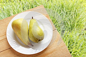 Fresh ripe pears on wooden table and on green grasses background. Healthy natural food. Top view with copy space