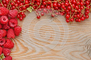 Fresh ripe raspberries and currand on wooden table