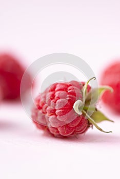 Fresh ripe raspberry with leaf on pink background