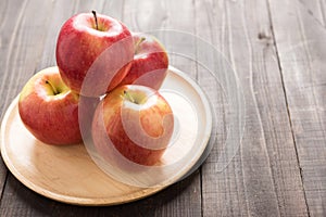 Fresh ripe red apples on dish wooden background. Copy space for
