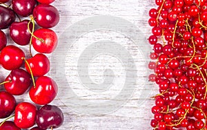 Fresh ripe red currants and cherries on rustic wood background.