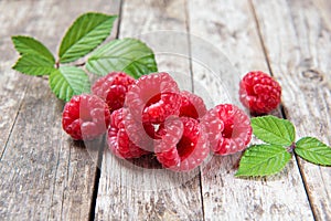 Fresh raspberries with leaves on a wooden background, closeup