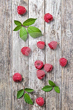 Fresh raspberries with leaves on a wooden background, top view