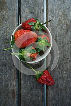Fresh ripe red strawberries in bowl on wooden table