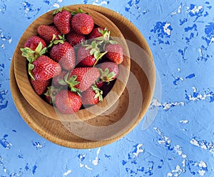 Fresh ripe red strawberries in a brown wooden round plate