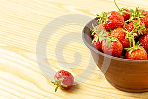 Fresh ripe red strawberries in a clay bowl on a wooden background