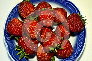 Fresh ripe red strawberries lie in a plate close-up