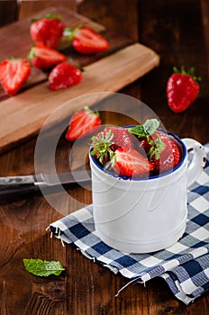 Fresh ripe red strawberries in white enamel cup