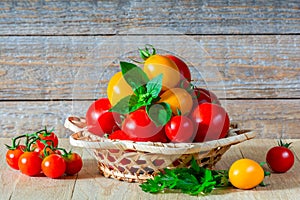 Fresh ripe red and yellow tomatoes in a wicker plate on a wooden table