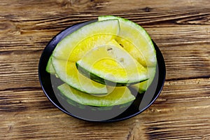 Fresh ripe sliced yellow watermelon in a plate on wooden table