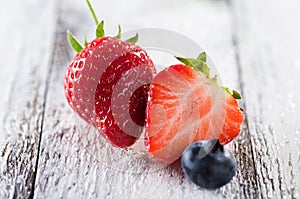 Fresh ripe strawberries and blueberries on plate on white