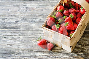 Fresh ripe strawberries in a wooden basket on a wooden background. Organic juicy berries