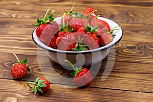 Fresh ripe strawberry in white bowl on wooden table