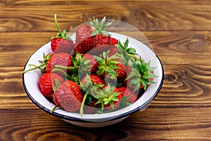 Fresh ripe strawberry in white bowl on wooden table