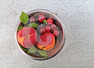 Fresh ripe summer berries and fruits, peaches, apricots, cherry and strawberry in a round plate