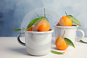 Fresh ripe tangerines with green leaves and mugs