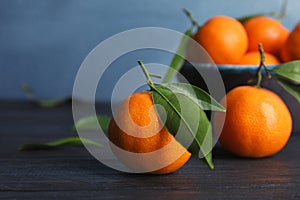 Fresh ripe tangerines with green leaves on table