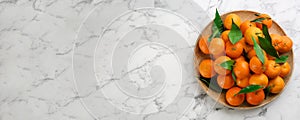 Fresh ripe tangerines and green leaves on white marble table, top view with space for text. Banner design