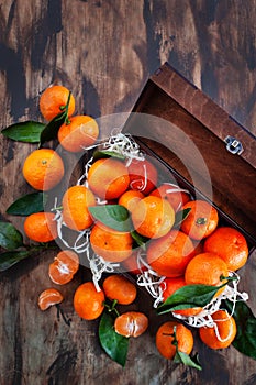 Fresh ripe tangerines with leaves in wooden box