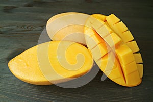 Fresh Ripe Thai Nam Dok Mai Mangoes Whole Fruit and Cut in Half on Dark Brown Wooden Background