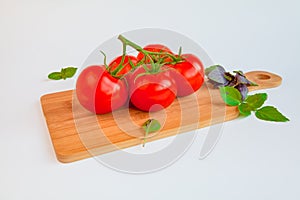 Fresh and ripe tomatoes and basil on cutting board