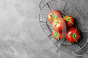 Fresh ripe tomatoes in a basket on a concrete tectrut background. Top view.