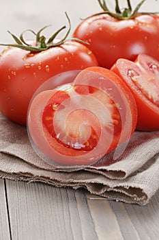 Fresh ripe tomatoes with halfs on wood table