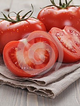 Fresh ripe tomatoes with halfs on wood table