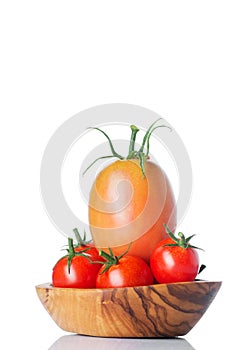Fresh ripe tomatoes in wood bowl isolated on white background.