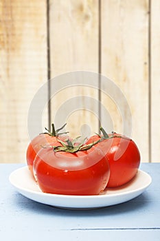 Fresh ripe tomatoes on wooden table and on background of wooden wall. Copy space. Organic vegetables for healthy breakfast or dinn
