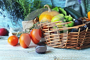 Fresh ripe vegetables and fruits in a basket, on a wooden table