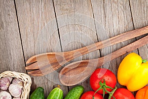 Fresh ripe vegetables and utensils on wooden table