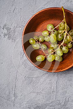 Fresh ripe white grape berries in wooden bowl on stone concrete background