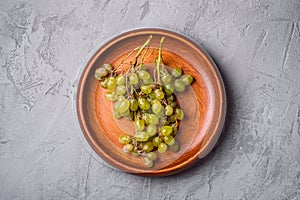 Fresh ripe white grape berries in wooden plate on stone concrete background