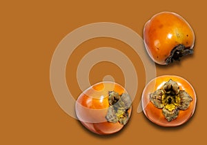 Fresh ripe whole persimmon, sharon on yellow orange background with copy space for text, healthy vegetarian diet top view