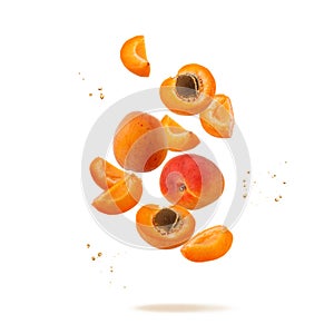 Fresh ripe whole and sliced apricot fruits with juice drops flying falling isolated on white background