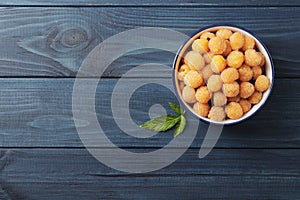 Fresh ripe yellow raspberries in bowl on blue wooden