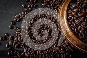 Fresh roasted arabica and robusta coffee beans. Coffee in a wooden bowl on a dark wood background