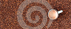 Fresh roasted coffee beans background. Top view. Horizontal banner with cup of coffee.