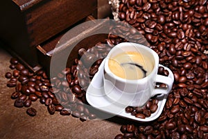 Fresh roasted coffee beans in burlap sack, coffee cup and grinder on dark background.